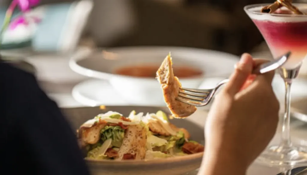 A person holds a fork with chicken over a salad in a restaurant setting at Chattleton Place in San Pablo, CA.